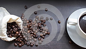 Hot coffee cup and coffee beans roasting on the wooden table