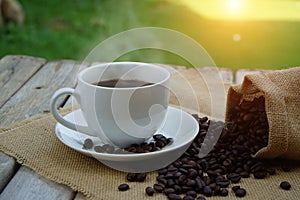 Hot Coffee cup and coffee beans roating on the wooden table