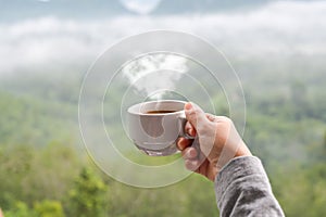 Hot coffee cup with heart shape steam in hand of woman