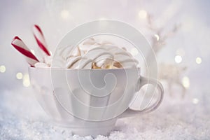 Hot Coffee cup with marshmallows and red candy cane on a frosty winter background. Christmas holidays background.