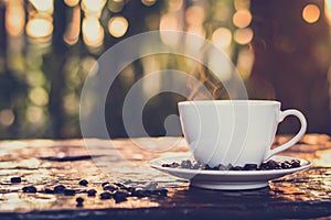 Hot coffee in the cup on old wood table with blur dark green nature background