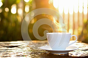 Hot coffee in the cup on old wood table with blur nature background