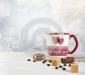 Hot coffee cup and sweets over frosted winter background