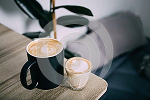 Hot coffee cups of latte art, coffee on the wooden table bedside table in the morning