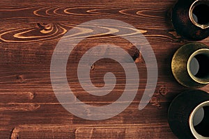 Hot coffee in different kind shabby turkish pots cezve with copy space on brown old wooden board background, top view.