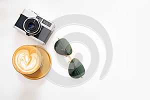 Hot coffee with film camera and sunglasses on a white background, top view