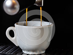 Hot coffee flow into a cup on espresso machine.