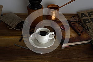Hot coffee, glasses, fountain pen, book and coffee beans on a wooden tray