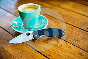 Hot coffee in a green cup with saucer and Knife on wooden table background.coffee cup and Knife on a wood background with copy spa