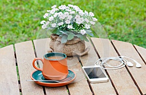 Hot coffee and headphone and smart phone on the wooden table.