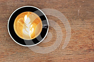 Hot coffee with latte art. Top view on wooden table with copy space. Favorite caffeine beverage. Refreshment drink in morning.