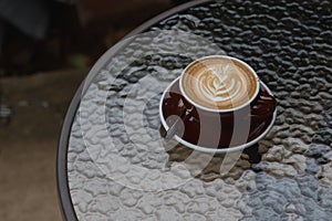 Hot coffee latte with beautiful latte art on ceramic glass in lo