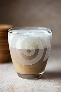 Hot coffee with milk foam in a transparent glass. Close up