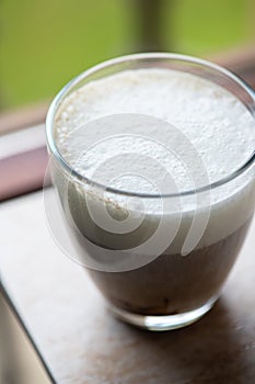 Hot coffee with milk foam in a transparent glass. Overhead view