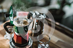 Hot coffee In Moka Pot on electric stove ,vintage coffee maker on wooden table at home, Selective focus