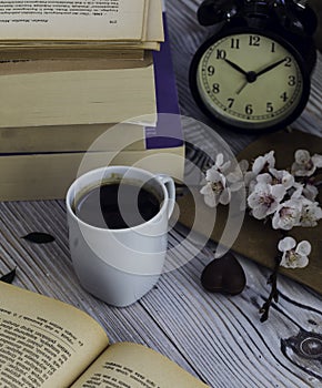 Hot coffee with old books and alarm clock