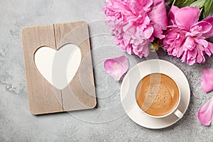 Hot coffee, peony flowers and heart shaped frame