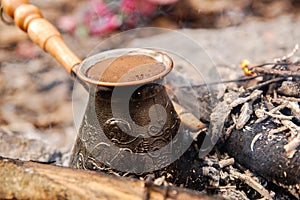 Hot coffee prepared in turk on open fire. Closeup.