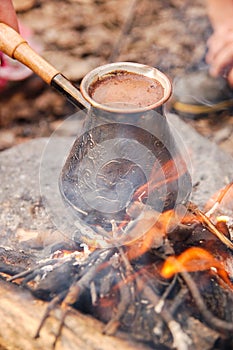 Hot coffee prepared in turk on open fire. Closeup