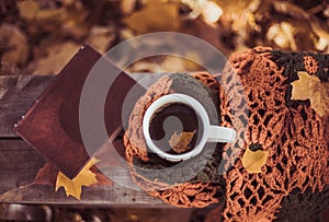 Hot coffee and red book with autumn leaves on wood background - seasonal relax concept