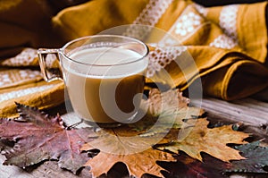 Hot coffee on rustic table with leaves.