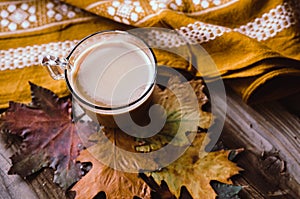 Hot coffee on rustic table with leaves.