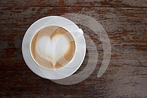 Hot coffee on table with heart shape on top of white cup from top view. Copy space
