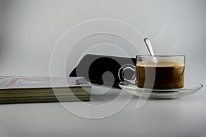 Hot coffee, tea on saucer, hot transparent cup of coffee cup and mobile phone with book next to it