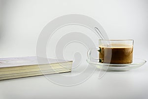 Hot coffee, tea on a saucer, transparent glass coffee cup with books by i