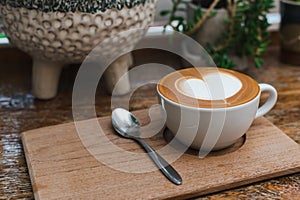 Hot coffee in white cup with coffee spoon on wooden tray. Copy space