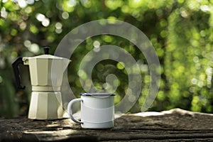 Hot coffee in a white enamel mug on an old wooden floor while camping in the forest. soft focus.shallow focus effect