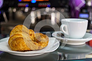 Hot croissant and coffee cup on saucer in a cafe