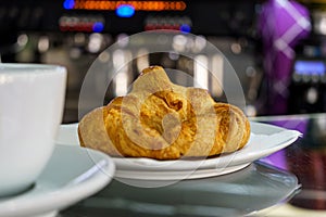 Hot croissant and coffee cup on saucer in a cafe