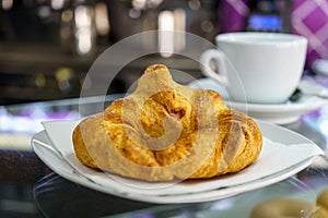 Hot croissant and coffee cup on saucer in a cafe