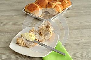 Hot cross buns, butter, knife and green napkin
