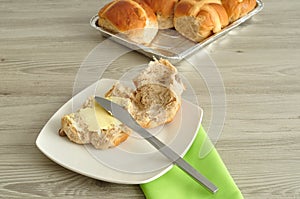 Hot cross buns, butter, knife and green napkin