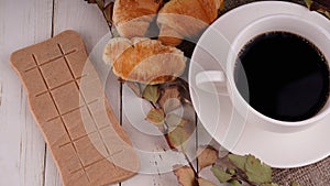 A hot cup of coffee with a bar of chocolate on the table in a cafe. Composition of a delicious coffee and sweet snack.