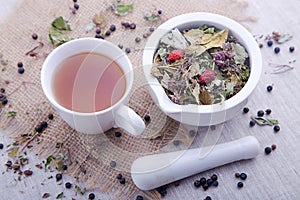 Hot cup of herbal and blackberry tea with white mortar with pestle