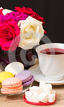 Hot cup of red tea and colored cakes