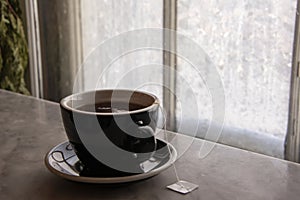 Hot cup of tea on a marble window sill in front of an Ice coated photo