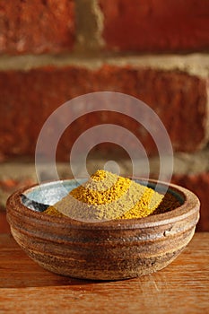 Hot curry powder spice in bowl on wooden table