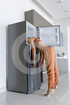 On a hot day, the girl cools with his head in the refrigerator. Broken air conditioner