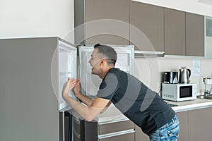 On a hot day, the guy cools with his head in the refrigerator. Broken air conditioner