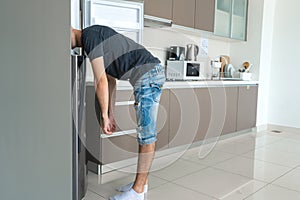 On a hot day, the guy cools with his head in the refrigerator. Broken air conditioner
