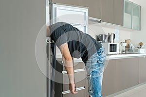 On a hot day, the guy cools with his head in the refrigerator. Broken air conditioner