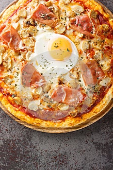 Hot delicious Pizza Bismarck with tomato sauce, melted cheese, egg, mushrooms, ham close-up on a wooden board on the table.