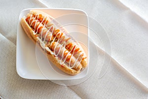 Hot dog with bun and ketchup, mayonnaise on white plate. Sausage sandwich for lunch. Fast food concept