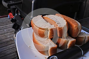 Hot dog buns on a plate beside a barbeque