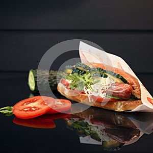 Hot-dog with fresh vegetables and cheese in paper