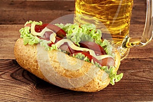Hot dog with glass of beer on wooden board photo